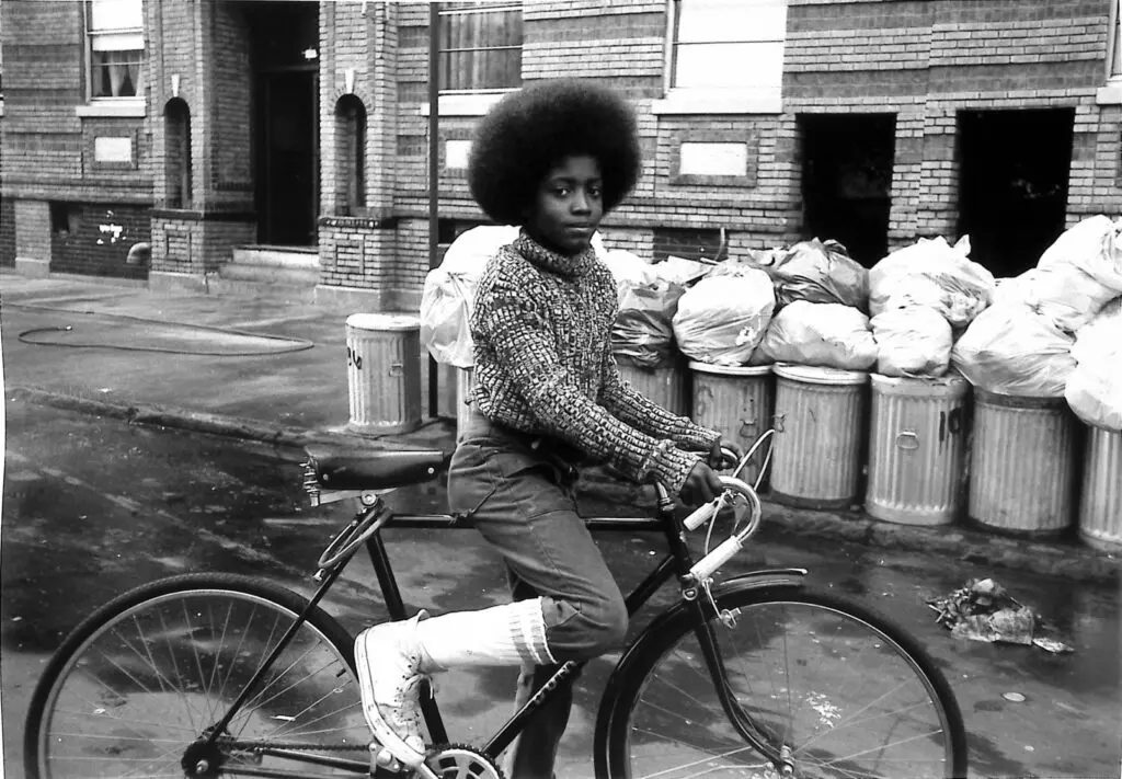 Arlene Gottfried (1950–2017) Boy with Afro on Bicycle in front of Trash Cans, 1975 Gelatin silver print The New York Historical, Gift of Sally Klingenstein Martell © Estate of Arlene Gottfried. Powerful images for Black History Month.