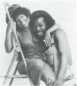 Nick Ashford & Valerie Simpson hugging eachother; Valerie sits on a ladder