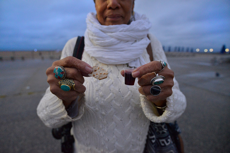 June Truesdale holds wine and crackers symbolizing the body of Christ- during a ritual at MAAFA ceremony in Far Rockaway at Reese beach organized by the St Paul's Community Baptist Church, Brooklyn, NYC